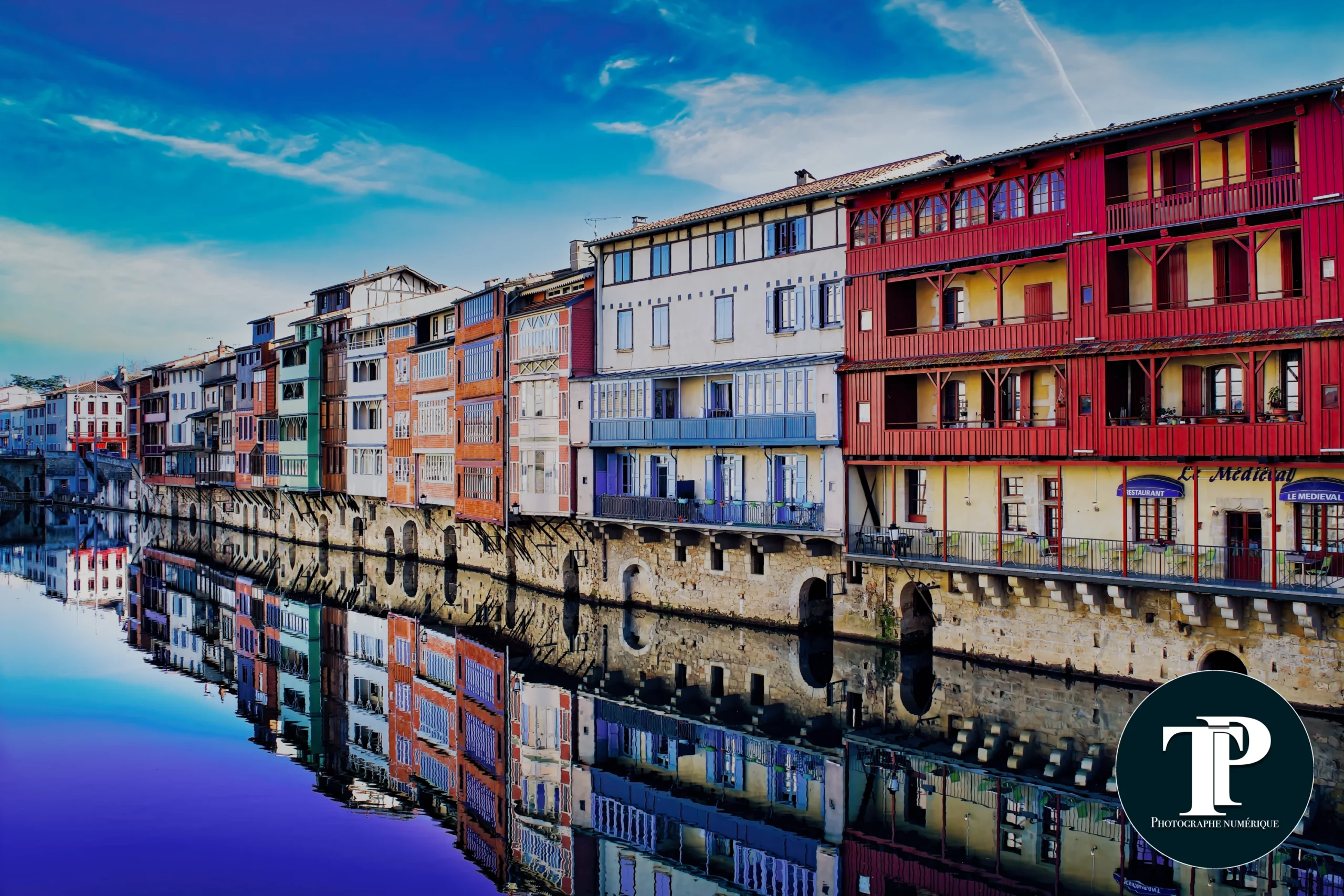 maisons-colorees-castres-riviere-tarn.webp Maisons colorées médiévales en bord de rivière à Castres, Occitanie, avec reflets dans l’eau.